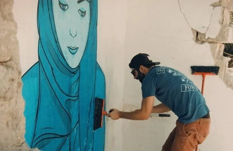Umelec dotvára maľbu v štvrti Satwa